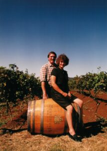 Ian and Merralea sitting on a barrel in the vineyard